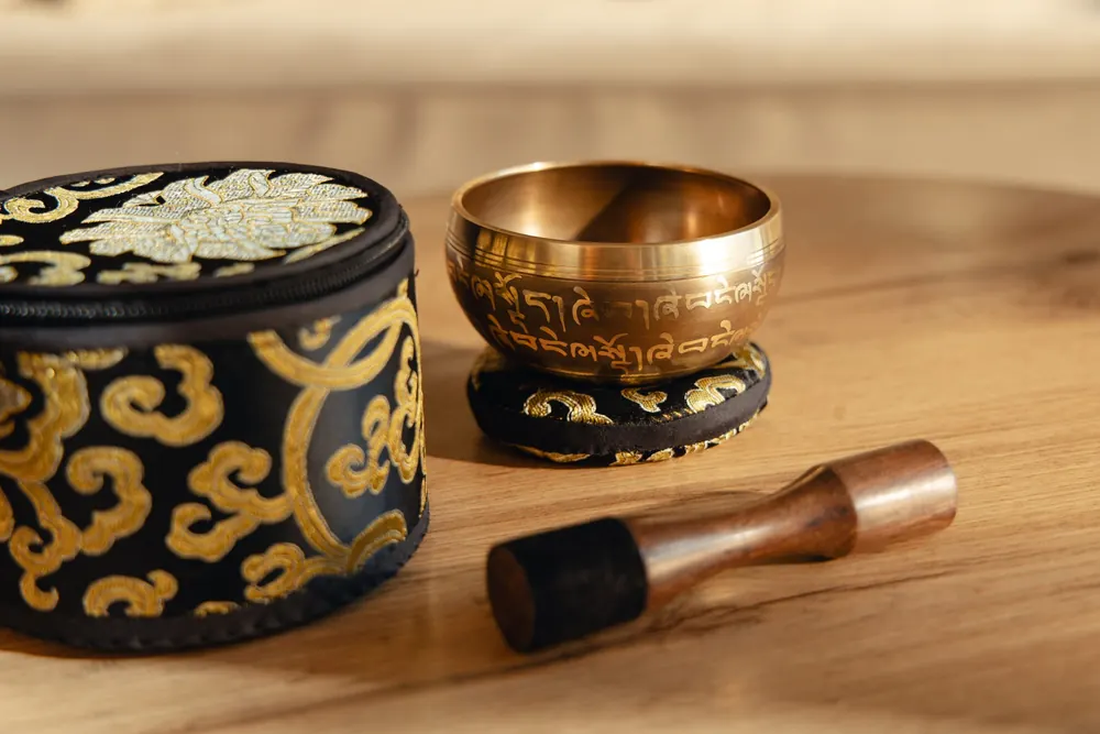 A singing bowl with its case and striker